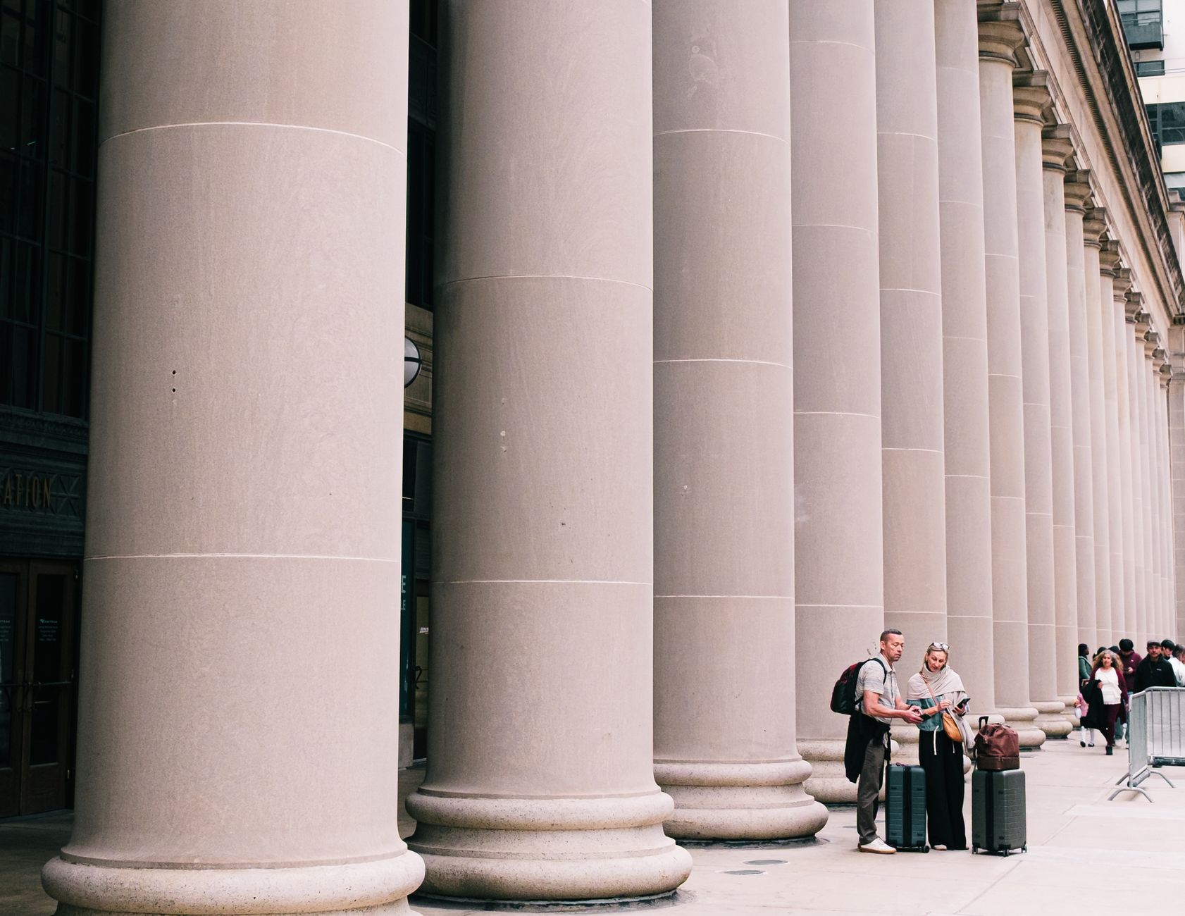 Stone columns of a courthouse with two people on the steps